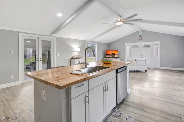 kitchen featuring french doors, wood counters, sink, a center island with sink, and stainless steel dishwasher