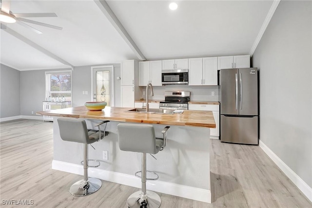 kitchen featuring light hardwood / wood-style flooring, wooden counters, white cabinetry, a kitchen breakfast bar, and stainless steel appliances