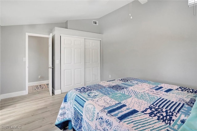 bedroom featuring light hardwood / wood-style flooring, vaulted ceiling, and a closet