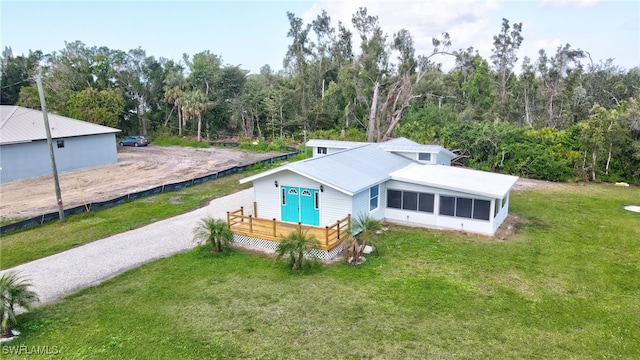 view of front of house featuring a wooden deck, a sunroom, and a front yard