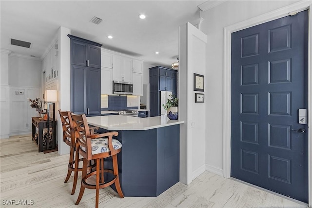 kitchen with a kitchen breakfast bar, decorative backsplash, kitchen peninsula, stainless steel appliances, and crown molding