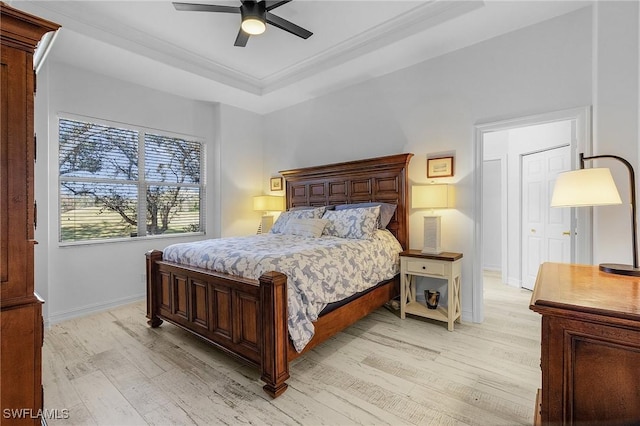 bedroom with crown molding, light hardwood / wood-style flooring, a raised ceiling, and ceiling fan