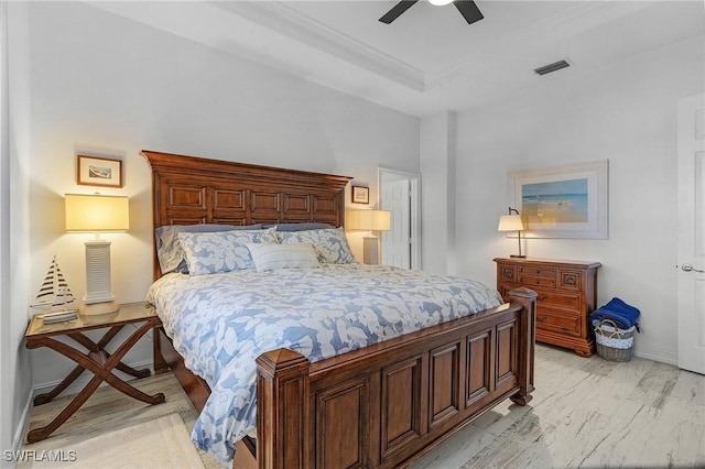 bedroom with ceiling fan, light hardwood / wood-style floors, and a tray ceiling