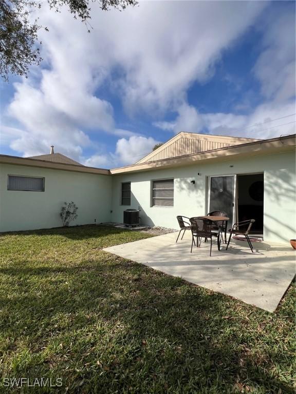 rear view of property featuring central AC unit, an outdoor fire pit, a lawn, and a patio area