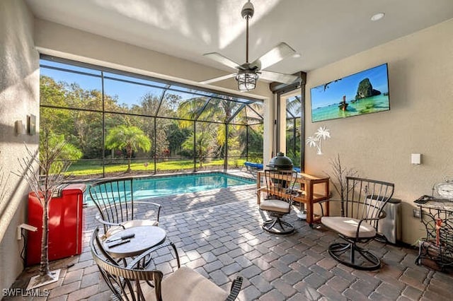 view of pool featuring a patio area, ceiling fan, and glass enclosure