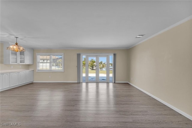 unfurnished living room with french doors, ornamental molding, and light wood-type flooring