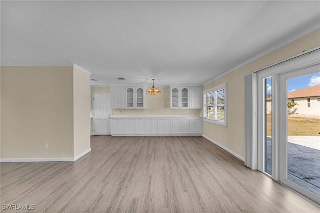 unfurnished living room with crown molding, a chandelier, and light hardwood / wood-style floors