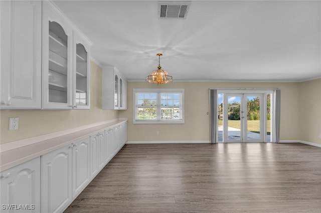 unfurnished dining area with crown molding, wood-type flooring, and french doors