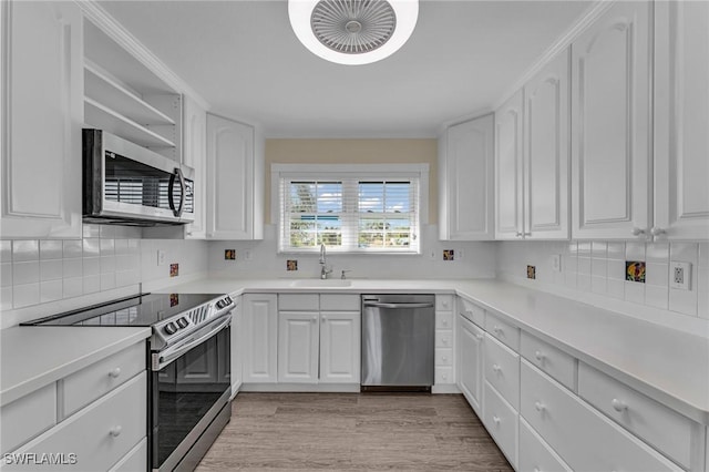 kitchen featuring sink, crown molding, white cabinetry, stainless steel appliances, and light hardwood / wood-style floors