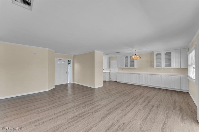 unfurnished living room featuring ornamental molding and light hardwood / wood-style floors