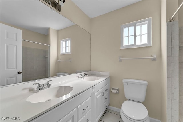 bathroom featuring vanity, tile patterned flooring, toilet, and tiled shower