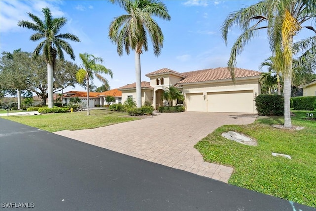 mediterranean / spanish-style home with a garage, stucco siding, decorative driveway, and a front yard