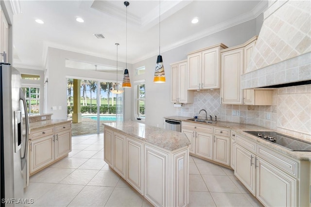 kitchen with a sink, a kitchen island, appliances with stainless steel finishes, decorative light fixtures, and cream cabinetry