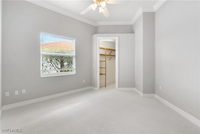 unfurnished bedroom with baseboards, a spacious closet, light carpet, and crown molding