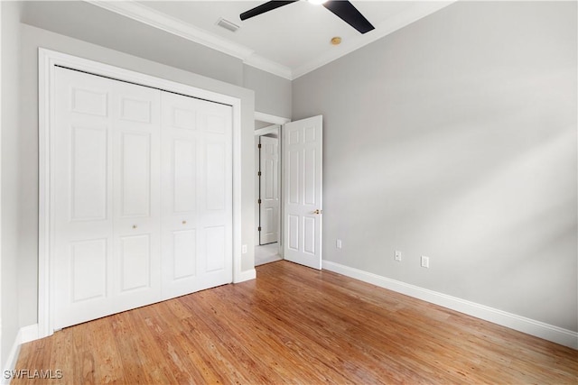 unfurnished bedroom with baseboards, visible vents, crown molding, wood finished floors, and a closet