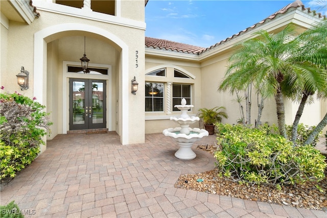 property entrance with stucco siding, french doors, and a tile roof