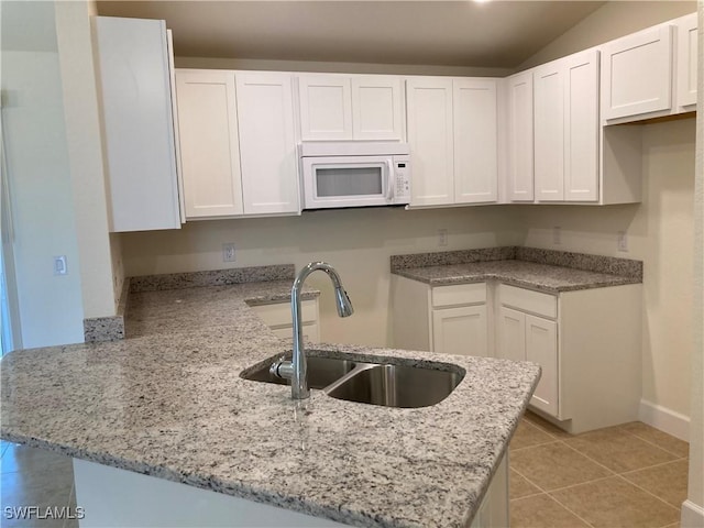 kitchen featuring white cabinetry, kitchen peninsula, sink, and light tile patterned floors