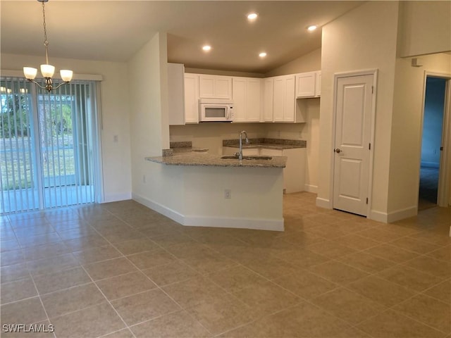 kitchen featuring vaulted ceiling, sink, white cabinets, hanging light fixtures, and kitchen peninsula