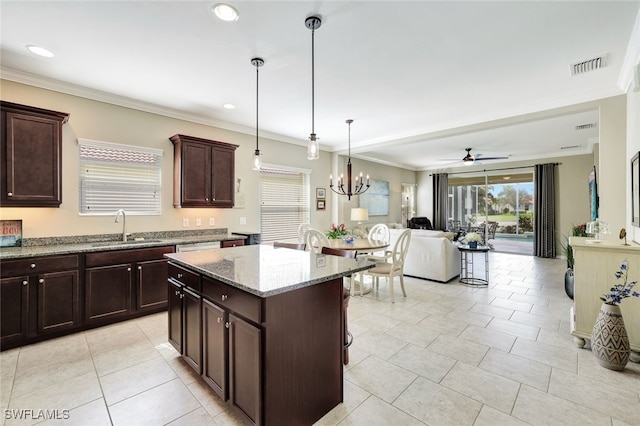 14558 Manchester Dr, Naples, FL 34114 - kitchen featuring decorative light fixtures, sink, a center island, light stone counters, and crown molding