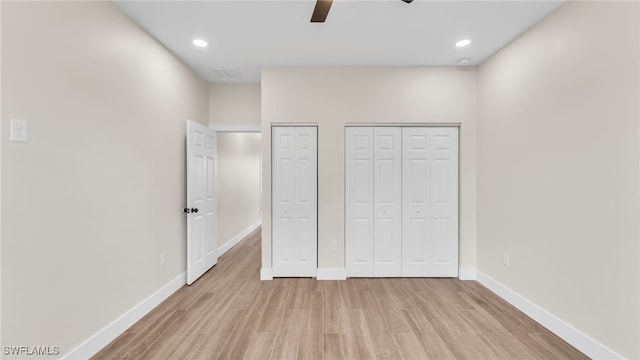 unfurnished bedroom with ceiling fan, light hardwood / wood-style floors, and two closets