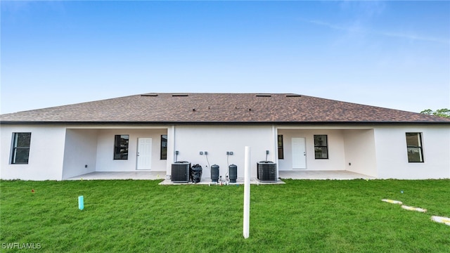 rear view of property with a lawn, a patio area, and central air condition unit