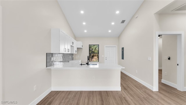 kitchen featuring sink, white cabinetry, tasteful backsplash, light hardwood / wood-style flooring, and kitchen peninsula