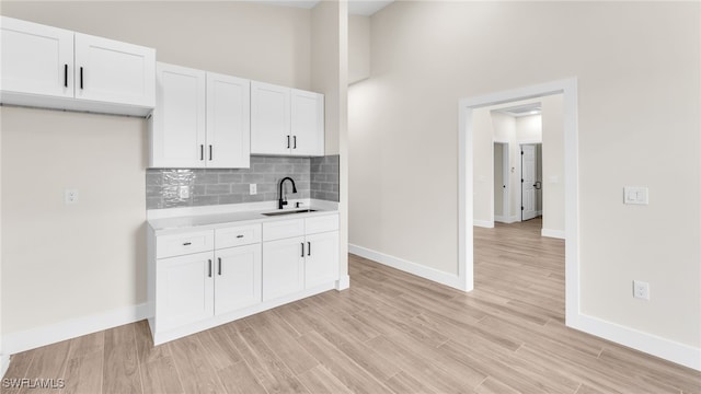 kitchen featuring tasteful backsplash, sink, white cabinets, and light wood-type flooring