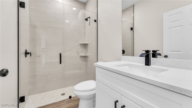 bathroom featuring vanity, wood-type flooring, walk in shower, and toilet