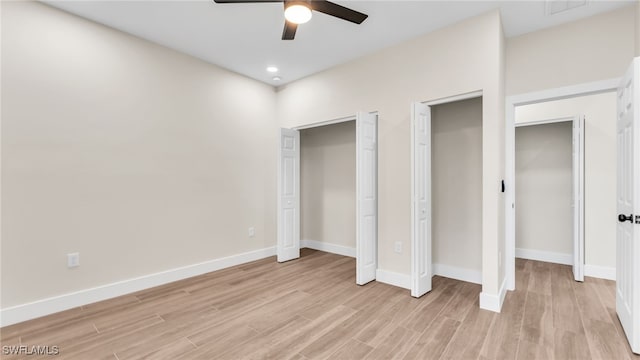 unfurnished bedroom with two closets, light hardwood / wood-style floors, and ceiling fan