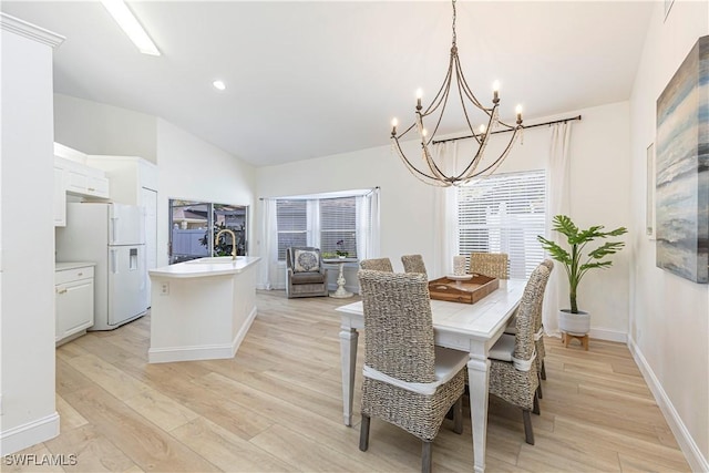 dining area with baseboards, a healthy amount of sunlight, vaulted ceiling, and light wood finished floors