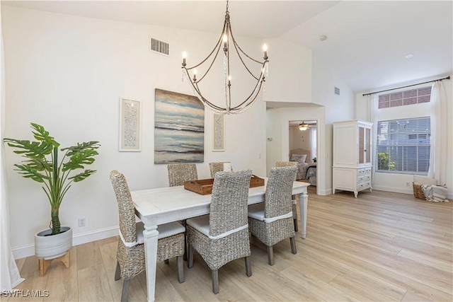 dining space featuring ceiling fan with notable chandelier, baseboards, visible vents, and light wood finished floors