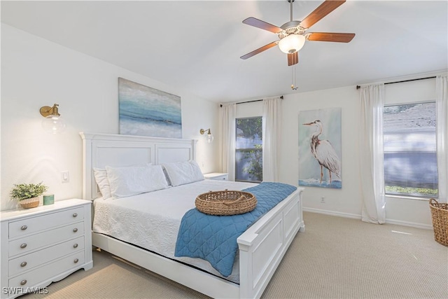 bedroom with multiple windows, a ceiling fan, baseboards, and light carpet