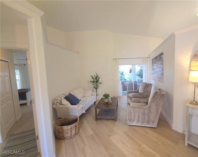 living room featuring baseboards, lofted ceiling, and light wood-style floors