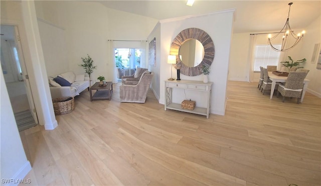 sitting room with a notable chandelier, baseboards, and light wood-style floors