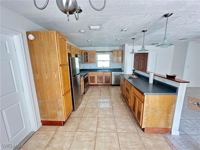 kitchen featuring pendant lighting, sink, light tile patterned floors, stainless steel appliances, and a textured ceiling