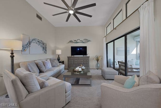 living room featuring light carpet, a towering ceiling, and ceiling fan