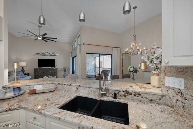 kitchen featuring white cabinetry, sink, light stone countertops, and hanging light fixtures