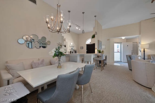 carpeted dining space with rail lighting, a towering ceiling, a notable chandelier, and breakfast area