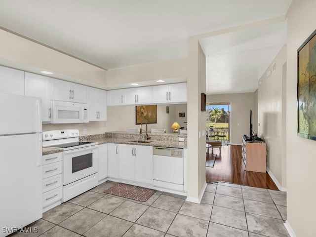 kitchen with white cabinetry, white appliances, light tile patterned flooring, and sink