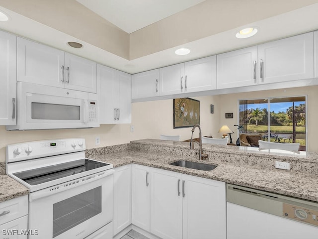 kitchen featuring light stone countertops, sink, white cabinets, and white appliances