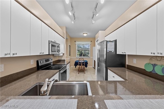 kitchen featuring appliances with stainless steel finishes, sink, white cabinets, and dark stone counters