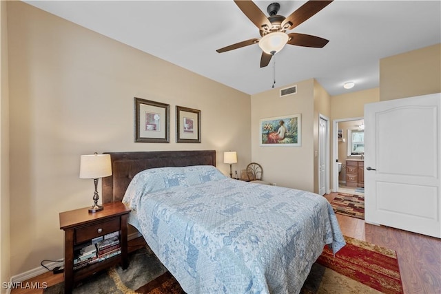 bedroom with ceiling fan, dark wood-type flooring, and ensuite bath