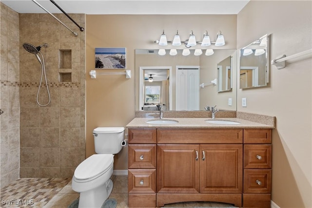 bathroom with tile patterned floors, vanity, toilet, and a tile shower