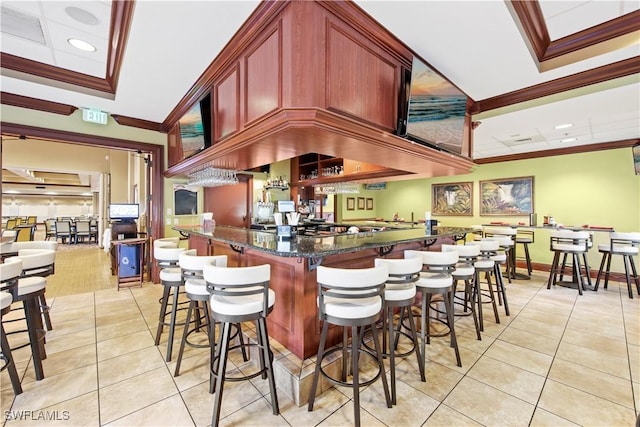 kitchen featuring crown molding, a breakfast bar area, light tile patterned floors, and kitchen peninsula