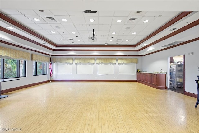 spare room with crown molding, a raised ceiling, and light wood-type flooring