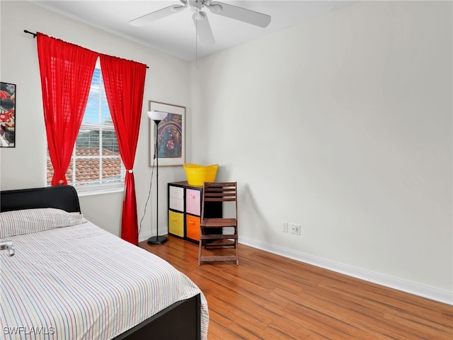 bedroom featuring wood finished floors, a ceiling fan, and baseboards