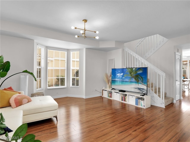 living area featuring baseboards, a notable chandelier, stairway, and wood finished floors