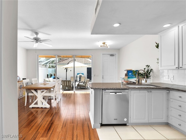 kitchen featuring decorative backsplash, stainless steel dishwasher, a ceiling fan, white cabinets, and a sink