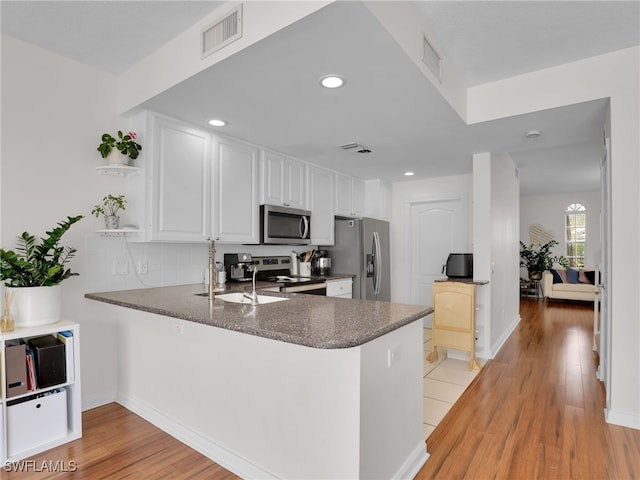 kitchen featuring visible vents, white cabinets, dark countertops, appliances with stainless steel finishes, and a peninsula