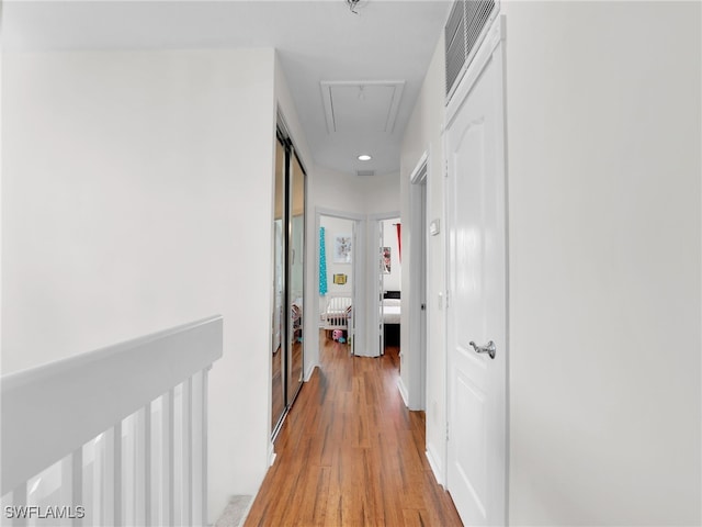 hallway with visible vents, light wood finished floors, attic access, and recessed lighting